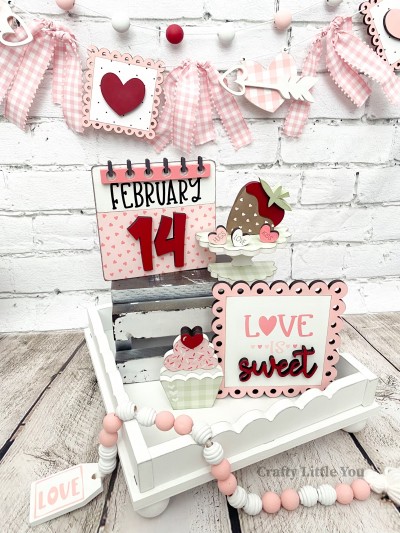 Unfinished kit measures apx. 5.75" tall and includes wooden MDF: 
* 1 scalloped edge sign
* 1 "sweet" wood word overlay
* 1 cupcake with liner and heart overlay
* 1 scalloped strawberry stand
* 3 small hearts with engraved words
* 1 calendar piece with "14" and wire notebook wood overlays
* Black and White vinyl (some is stencil) 
