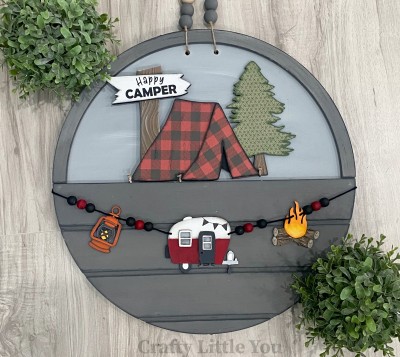 Unfinished kit measures apx. 7" tall and includes wooden MDF: 
* 1 main piece with connected tent, tree, and sign
* 1 tent opening overlay
* 1 sign overlay
* 1 hanging lantern
* 1 hanging camper with door and window overlays
* 1 hanging campfire
* Black vinyl
* 2 pieces Velcro