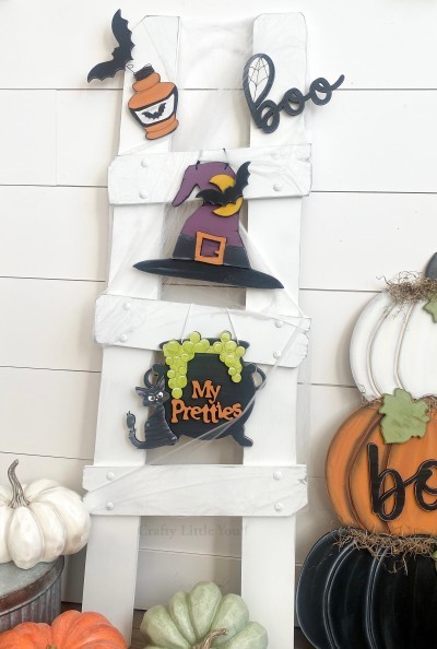 Unfinished kit measures apx. 9" tall on hanging pieces, and includes wooden MDF:
*1 witch hat main piece
*1 hat buckle overlay
*1 moon overlay
*2 bat overlays
*1 cauldron main piece
*1 cauldron bubbles overlay
*1 set of “My Pretties” wood word overlays
*1 black cat
*1 “boo” wood word with spiderweb
*1 potion bottle
*Top ladder kit pieces can be attached to ladder with Velcro or magnets.
Velcro dots can be purchased separately.
