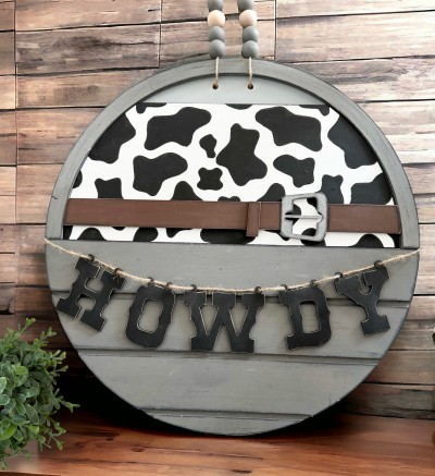 Unfinished kit is sized to fit the Front Door Circle and includes wooden MDF:
*1 cow print back board with engraved spots
*1 belt with loop overlay
*1 set of “HOWDY” hanging letters
*2 pieces Velcro