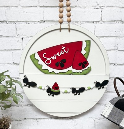 Unfinished kit is sized to fit the Front Door Circle and includes wooden MDF:
*2 watermelon wedges (1 large, 1 small)
*1 “Sweet” wooden word
*2 white rind overlays
*9 watermelon seeds
*4 ants
*2 pieces Velcro