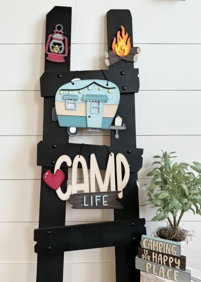 Unfinished kit measures apx. 8.5" tall on the camper, and includes wooden MDF:
*1 camper main piece with light string, door, window, and two awning overlays
*1 “Camp Life” sign
*1 heart overlay
*1 wood sign overlay
*1 set of “LIFE” wood letters
*1 campfire with flame overlay
*1 lantern with globe overlay