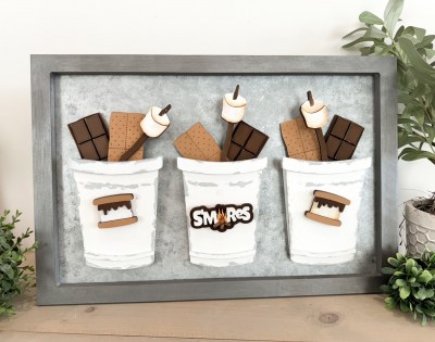 Unfinished kit includes wooden MDF:
*3 chocolate bars
*18 chocolate squares
*3 graham crackers
*3 sticks
*6 marshmallow pieces
*2 s’mores with chocolate drip and graham cracker overlays
*1 “S’MORES” word with back piece
*3 Velcro dots