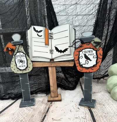 Unfinished kit measures apx. 10" on the spellbook and includes wooden MDF:
*1 spellbook with page overlays
*1 set of spiral binding overlays
*1 bookmark
*2 potion bottles
*2 potion bottle label overlays
*2 potion bottle stopper overlays
*2 tags with spider and crow
*3 stands
*3 bases